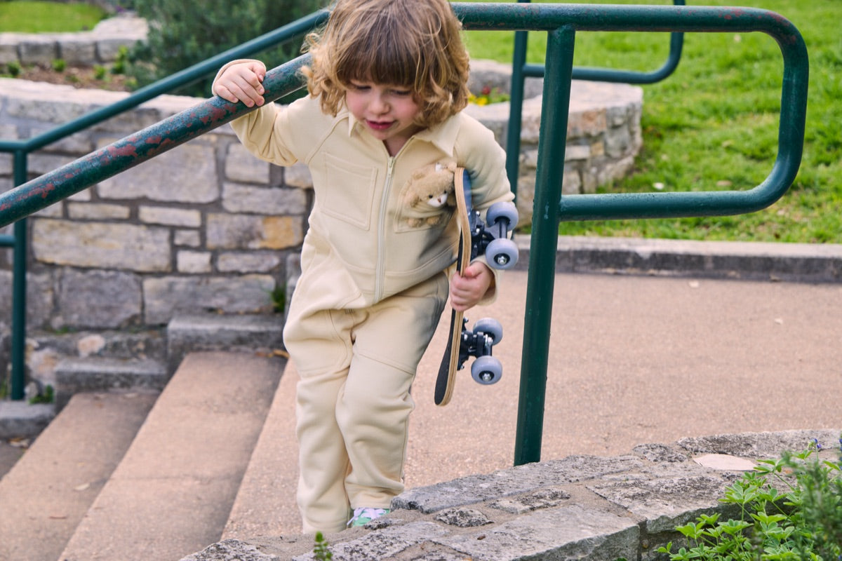 Child wearing Fox and Ocean Kids Collared Jumpsuit with bear pocket skateboarding outdoors